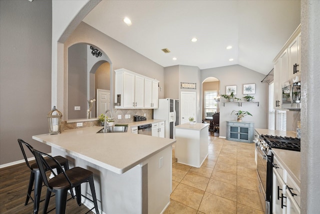 kitchen featuring stainless steel appliances, a kitchen island, a sink, vaulted ceiling, and decorative backsplash