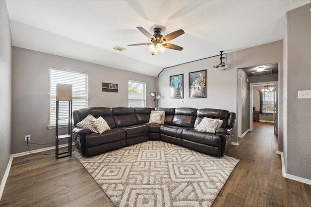 living room featuring vaulted ceiling, visible vents, ceiling fan, and wood finished floors