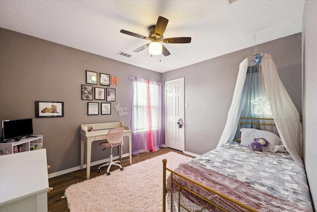 bedroom featuring a textured wall, wood finished floors, visible vents, and a ceiling fan