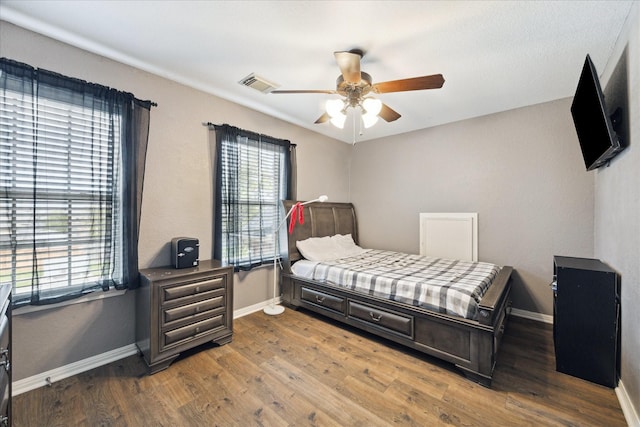 bedroom featuring a ceiling fan, wood finished floors, visible vents, and baseboards