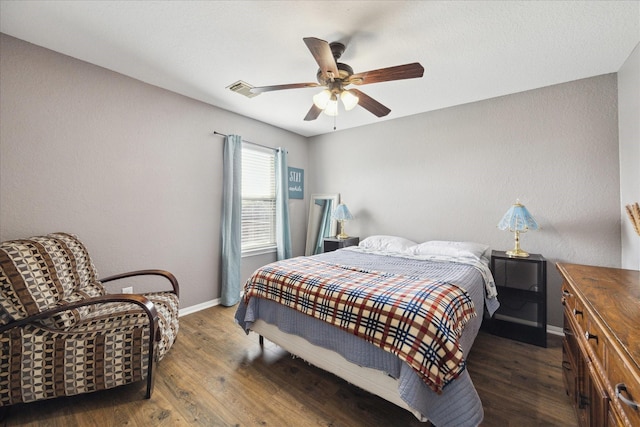 bedroom featuring a ceiling fan, wood finished floors, visible vents, and baseboards