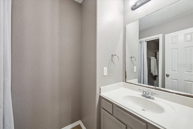 bathroom with a textured wall and vanity