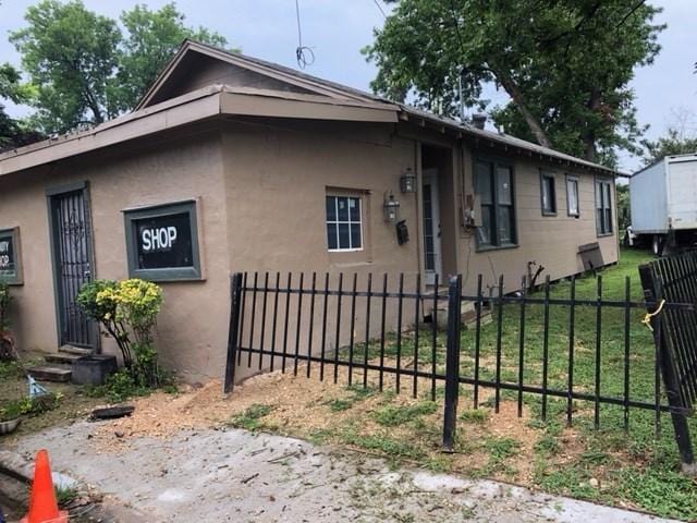 view of side of home featuring a fenced front yard, entry steps, and stucco siding