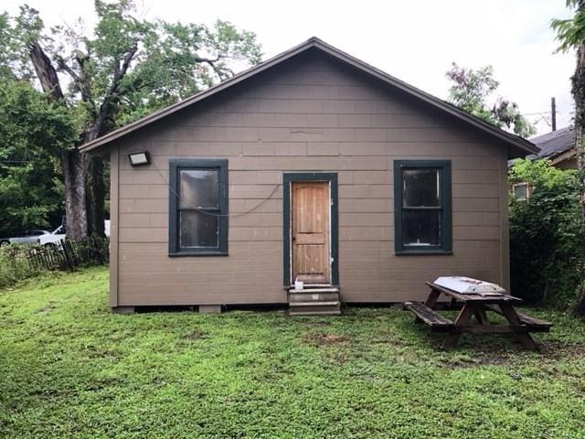 rear view of property featuring entry steps, fence, and a lawn