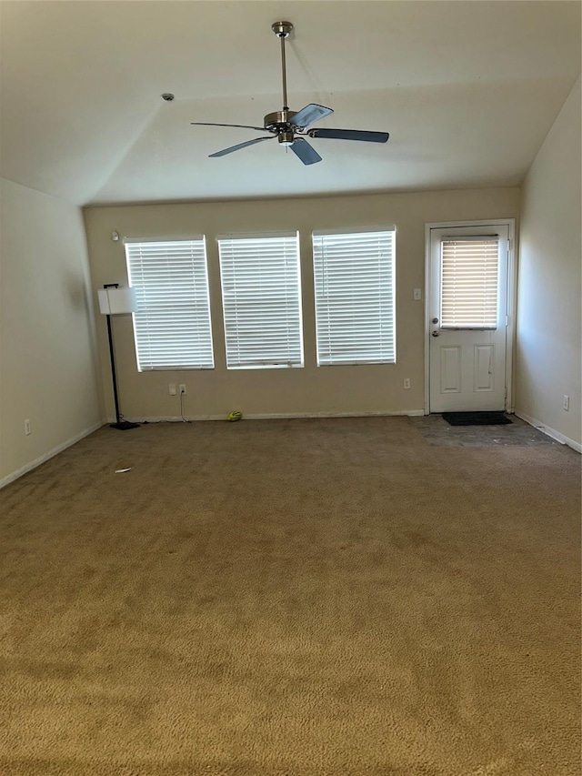 carpeted empty room featuring plenty of natural light, ceiling fan, baseboards, and lofted ceiling