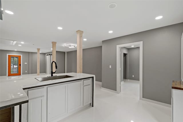 kitchen featuring baseboards, concrete floors, recessed lighting, a sink, and white cabinets