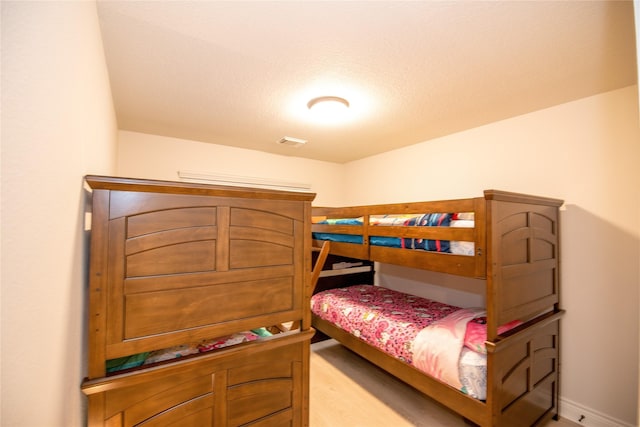 bedroom with baseboards, visible vents, and wood finished floors