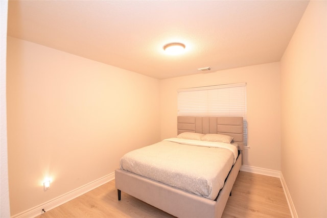 bedroom featuring visible vents, light wood-style flooring, and baseboards