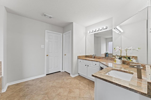 bathroom with visible vents, baseboards, a textured ceiling, and vanity