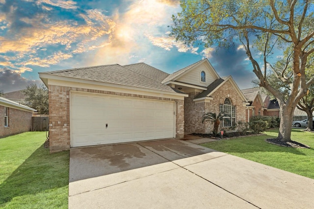 view of front of house featuring an attached garage, brick siding, a shingled roof, driveway, and a lawn