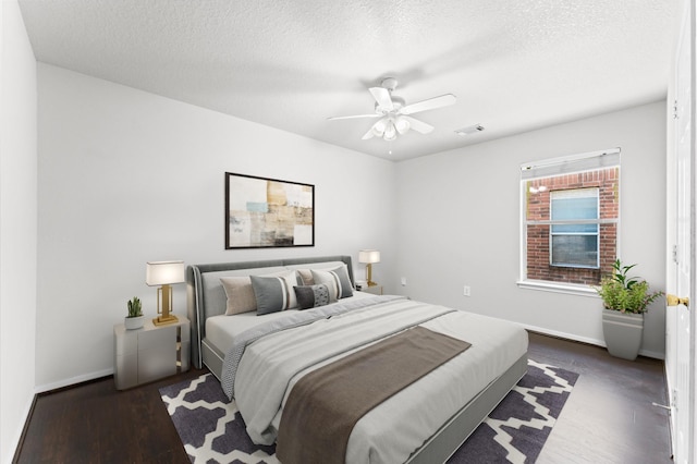 bedroom with a textured ceiling, wood finished floors, visible vents, and baseboards