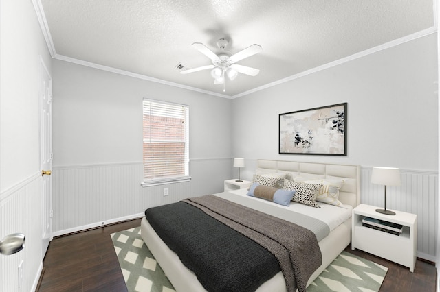 bedroom featuring wainscoting, ceiling fan, ornamental molding, wood finished floors, and a textured ceiling