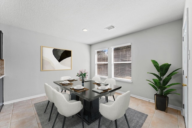 dining area featuring baseboards, visible vents, a textured ceiling, and light tile patterned flooring