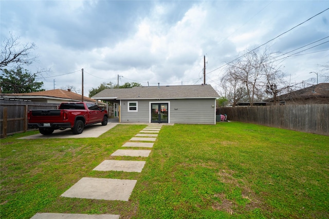 rear view of property featuring fence private yard, french doors, and a lawn