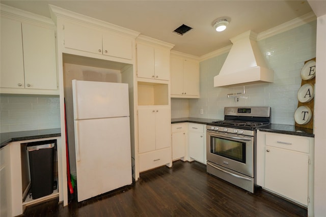 kitchen with dark wood-type flooring, premium range hood, stainless steel gas range, freestanding refrigerator, and crown molding