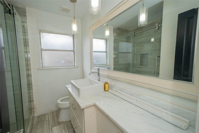 bathroom with wood finish floors, visible vents, toilet, a stall shower, and vanity