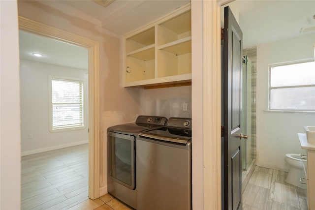 clothes washing area with laundry area, washer and clothes dryer, and baseboards