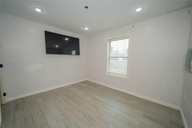 empty room with baseboards, wood finished floors, and recessed lighting