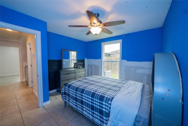 bedroom featuring attic access, light tile patterned flooring, ceiling fan, and baseboards