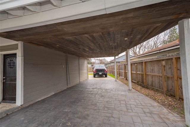 view of parking / parking lot featuring fence and a carport