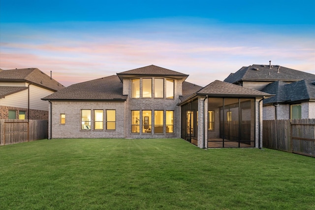 back of property with a sunroom, a fenced backyard, and a yard