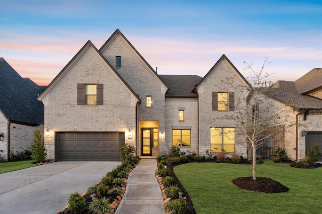 french provincial home with an attached garage, brick siding, driveway, and a front lawn