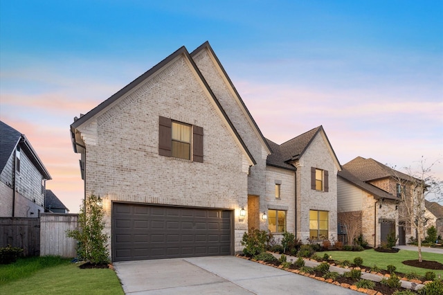 french country inspired facade with brick siding, a front yard, fence, a garage, and driveway