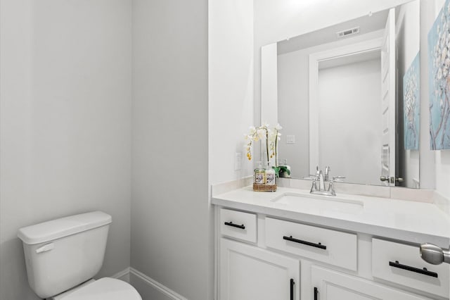 half bath with toilet, baseboards, visible vents, and vanity