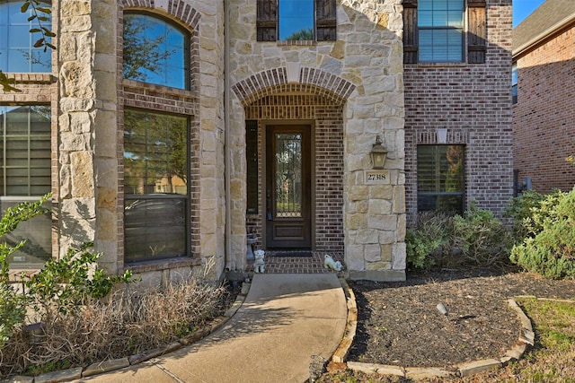 property entrance featuring stone siding and brick siding