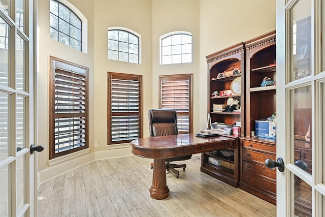 office featuring a high ceiling, baseboards, wood finished floors, and french doors