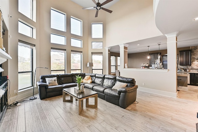 living area with ceiling fan, baseboards, light wood-style flooring, and ornate columns