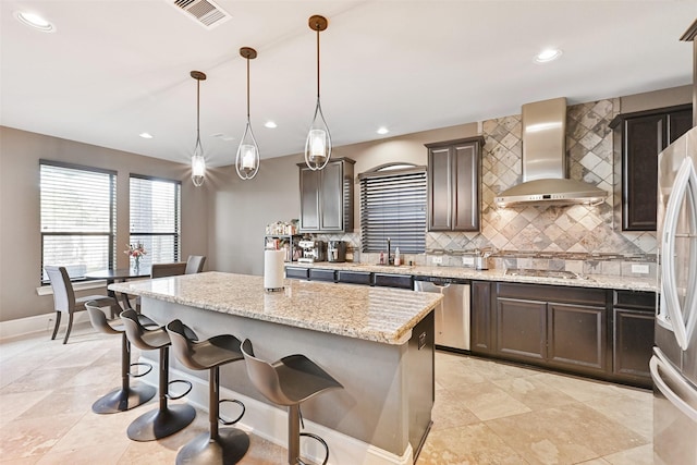 kitchen featuring a center island, visible vents, appliances with stainless steel finishes, decorative backsplash, and wall chimney exhaust hood