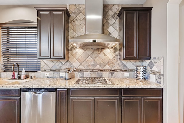 kitchen with appliances with stainless steel finishes, a sink, wall chimney exhaust hood, and dark brown cabinets