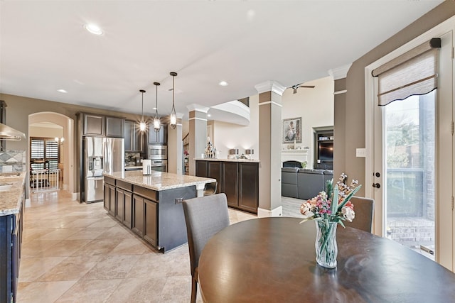 dining room featuring recessed lighting, a fireplace, arched walkways, and decorative columns