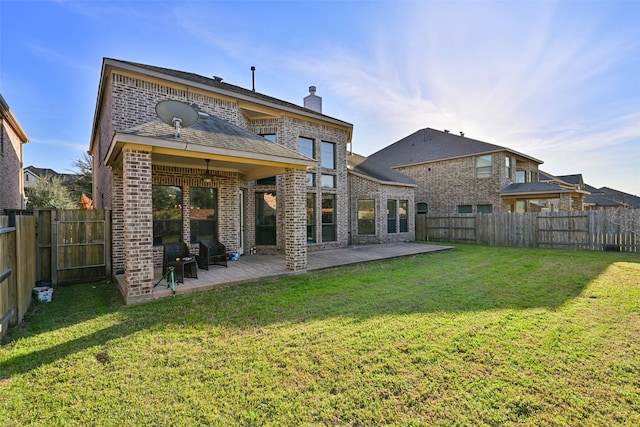 rear view of house with a ceiling fan, a lawn, a patio, a fenced backyard, and brick siding