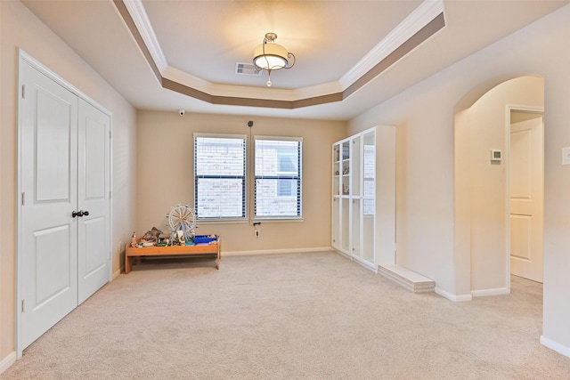 interior space with visible vents, a tray ceiling, arched walkways, and carpet flooring