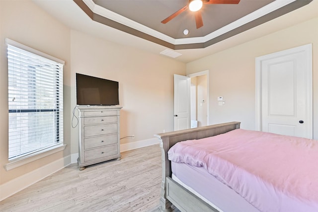 bedroom with ornamental molding, a raised ceiling, baseboards, and light wood finished floors