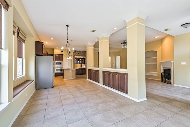 kitchen featuring a fireplace, a ceiling fan, open floor plan, appliances with stainless steel finishes, and ornate columns