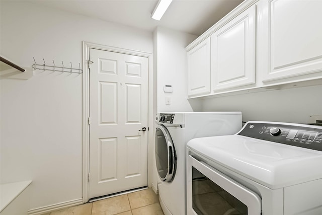 clothes washing area with washer and dryer, cabinet space, and light tile patterned floors