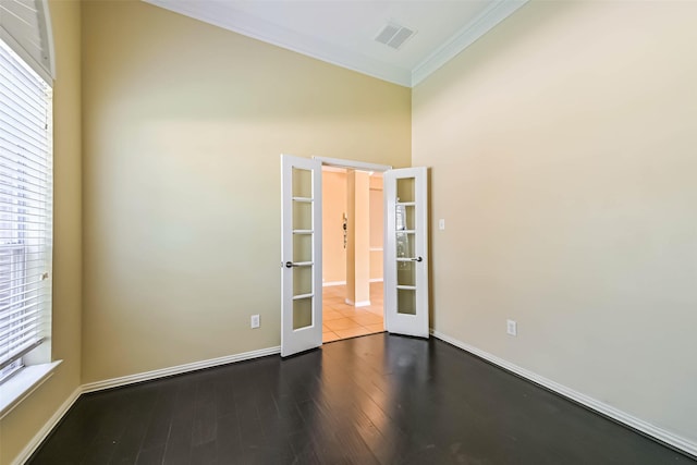 empty room with dark wood-style flooring, visible vents, baseboards, french doors, and crown molding