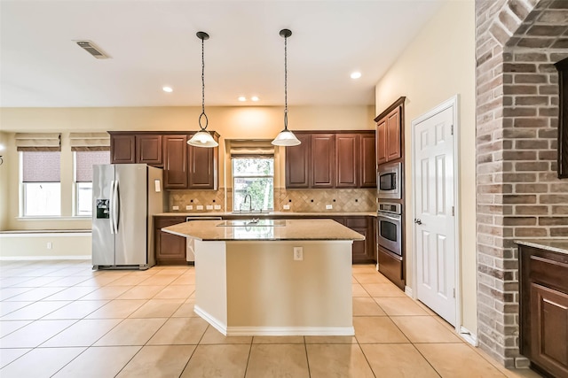 kitchen with light tile patterned floors, appliances with stainless steel finishes, a sink, and tasteful backsplash