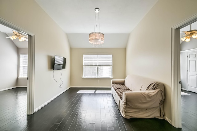 living area featuring a healthy amount of sunlight, dark wood-style flooring, and ceiling fan with notable chandelier