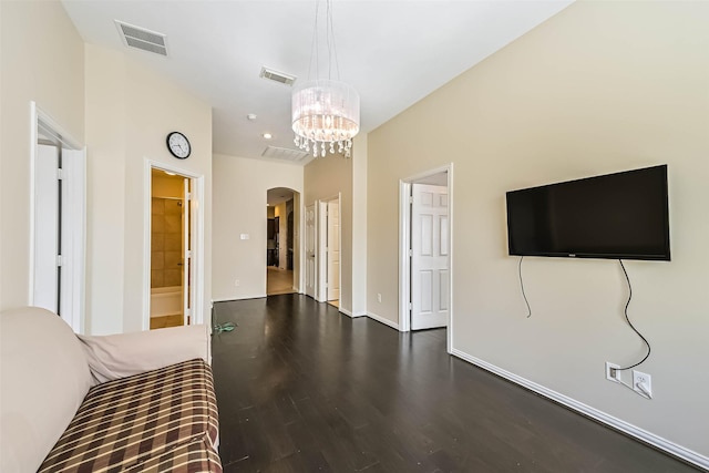 unfurnished bedroom featuring visible vents, arched walkways, wood finished floors, and a chandelier