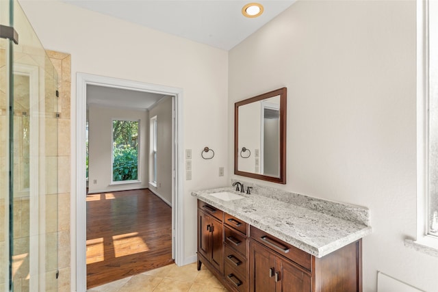 bathroom featuring tile patterned flooring, baseboards, tiled shower, and vanity