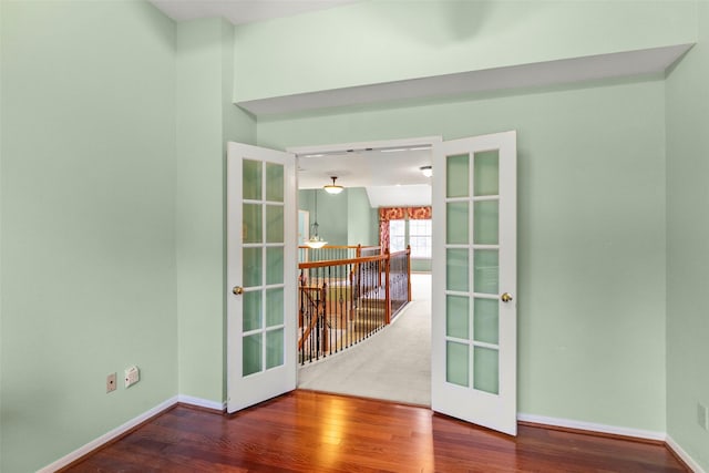 spare room featuring french doors, wood finished floors, and baseboards