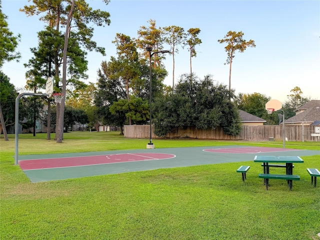 view of basketball court with community basketball court, fence, and a lawn