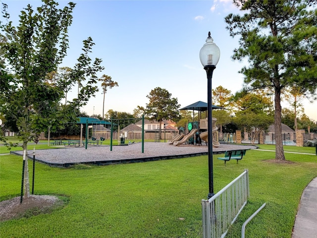 community play area with a lawn and fence