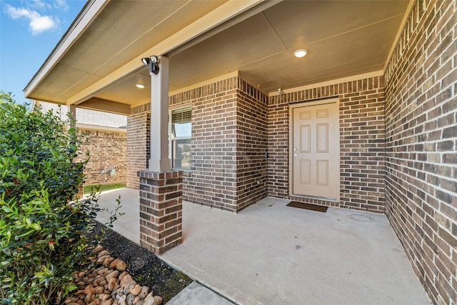 entrance to property with brick siding and a patio