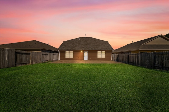 rear view of house with a patio, a lawn, and a fenced backyard