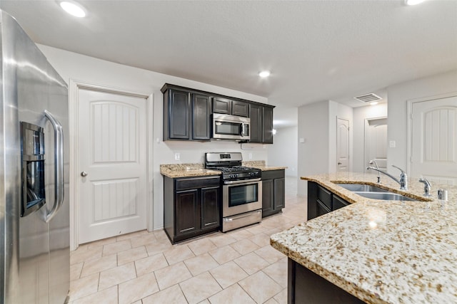 kitchen featuring recessed lighting, stainless steel appliances, a sink, visible vents, and light stone countertops